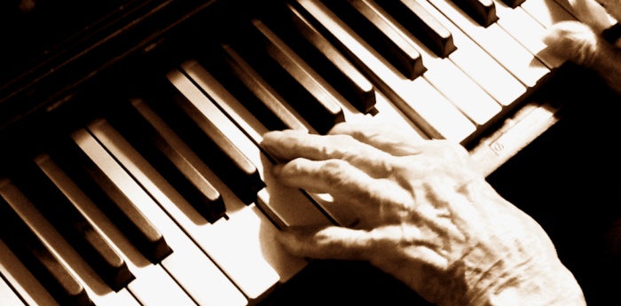 De handen van één van onze zestigplussers bespelen de pianotoetsen